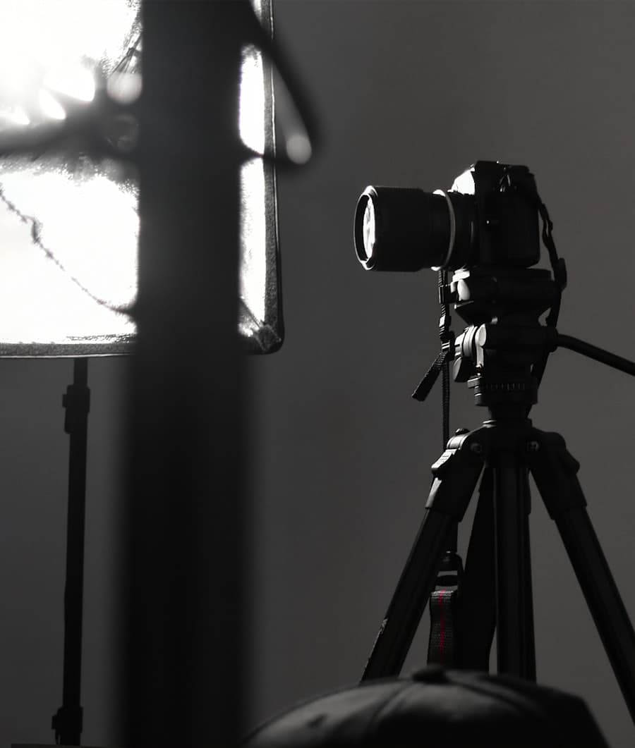 A cinema camera mounted on a tripod beside a lit softbox.