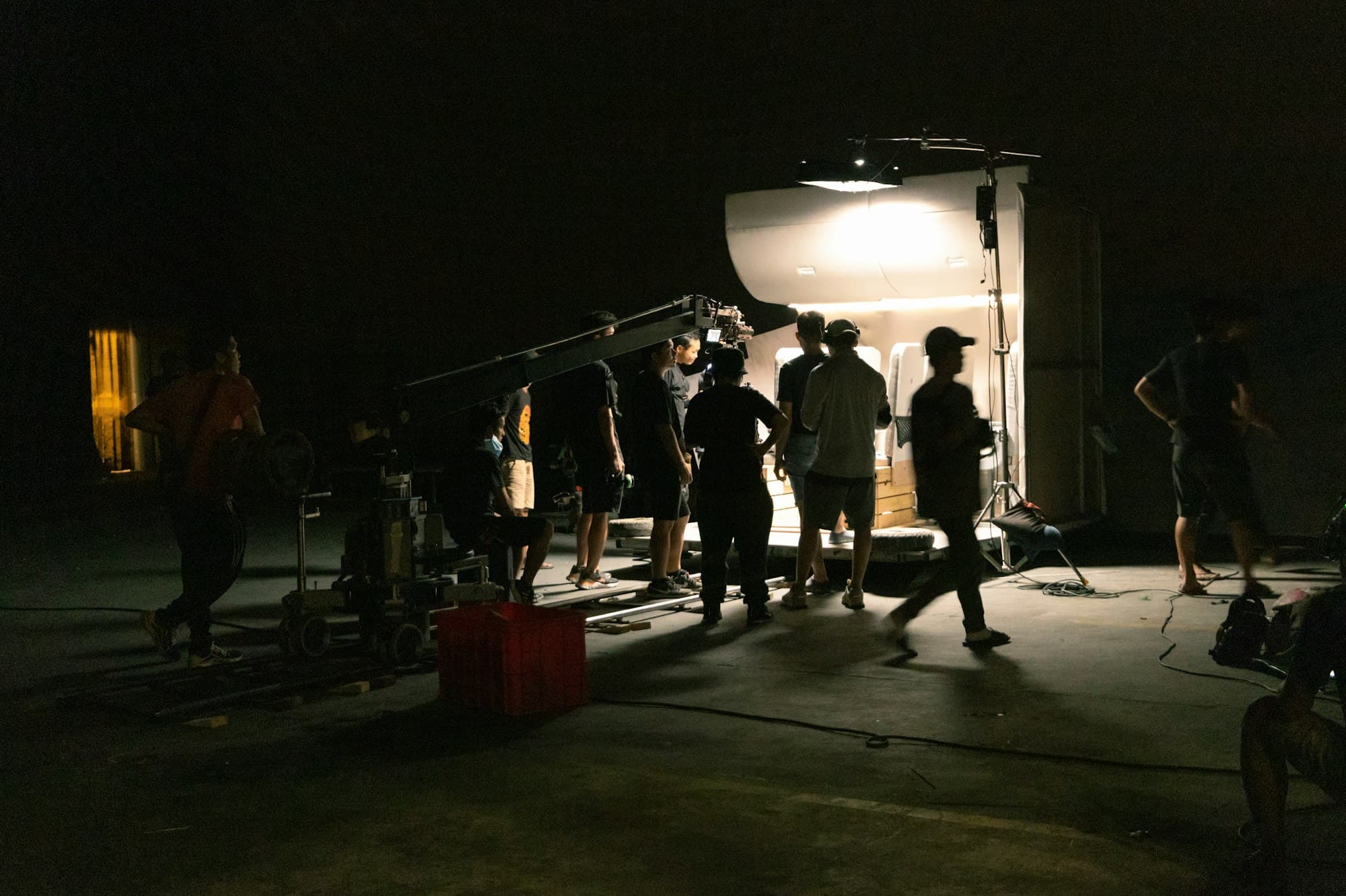 A film crew working around a lit set at night.